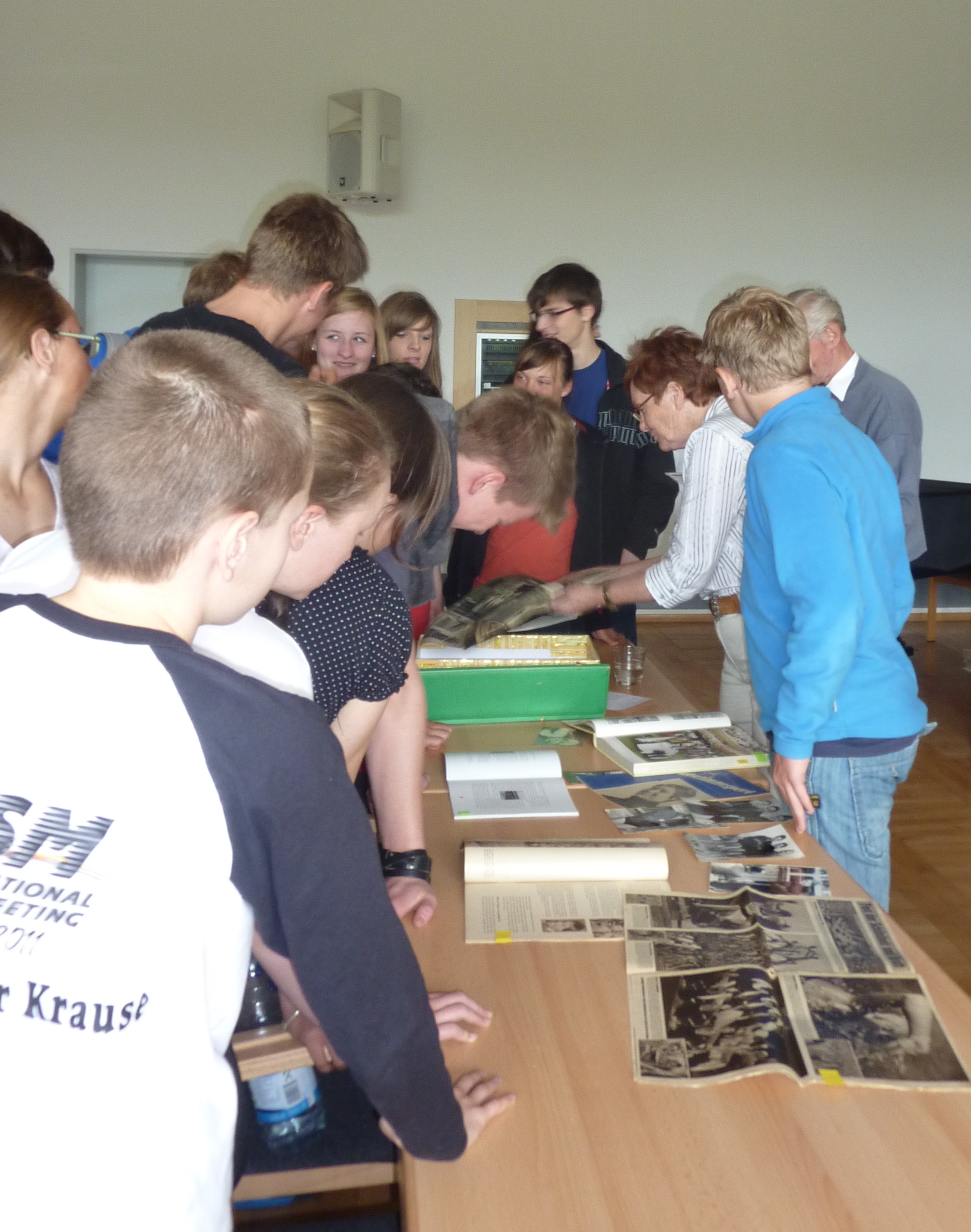 Die Schüler interessieren sich für die mitgebrachten Medaillen und Presseartikel von Frau Engelhardt.